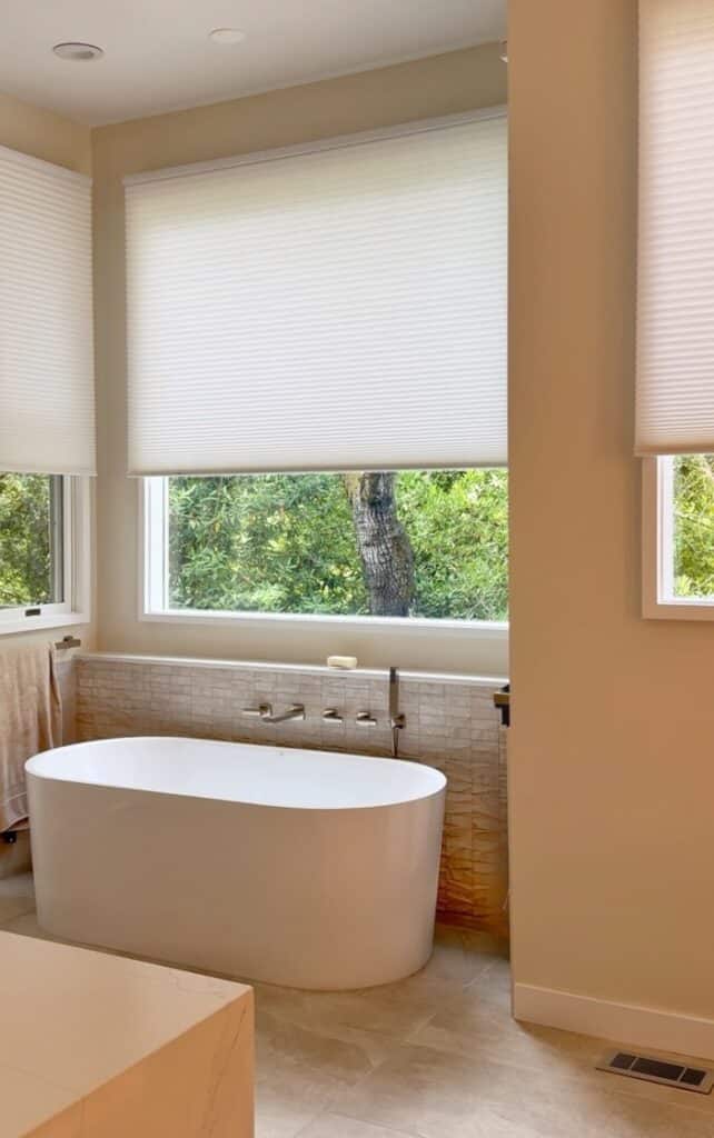 Motorized Hunter Douglas Duette shades lower at the touch of a button when privacy is needed in this elegant bathroom.