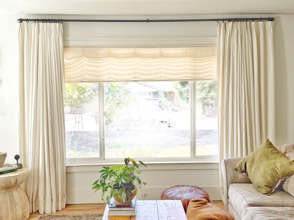 Lined linen drapes and sheer roman shades are the perfect layered solution to getting the right level of privacy from the street in this cozy living room.